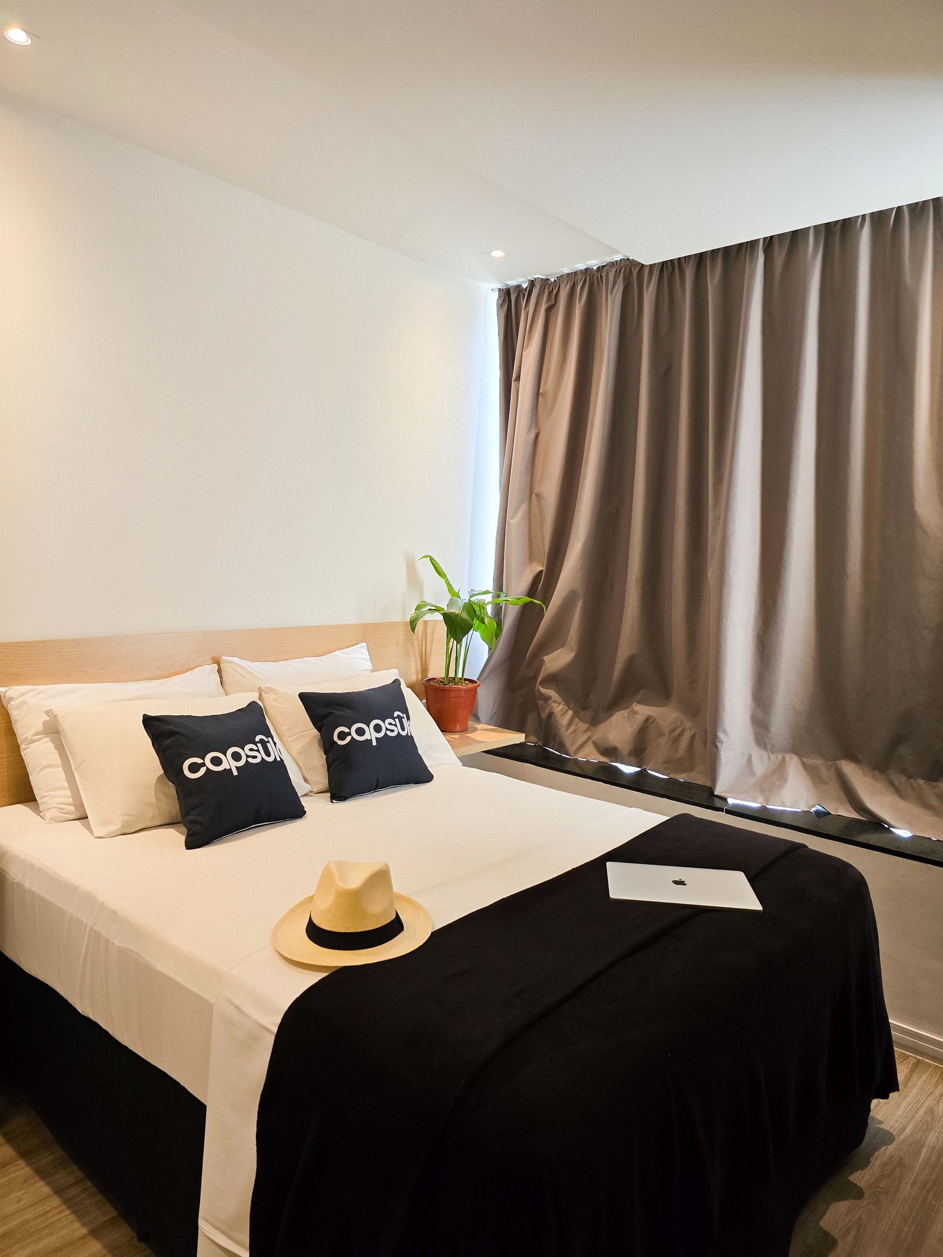 A bedroom with a bed , pillows , a hat and a window.