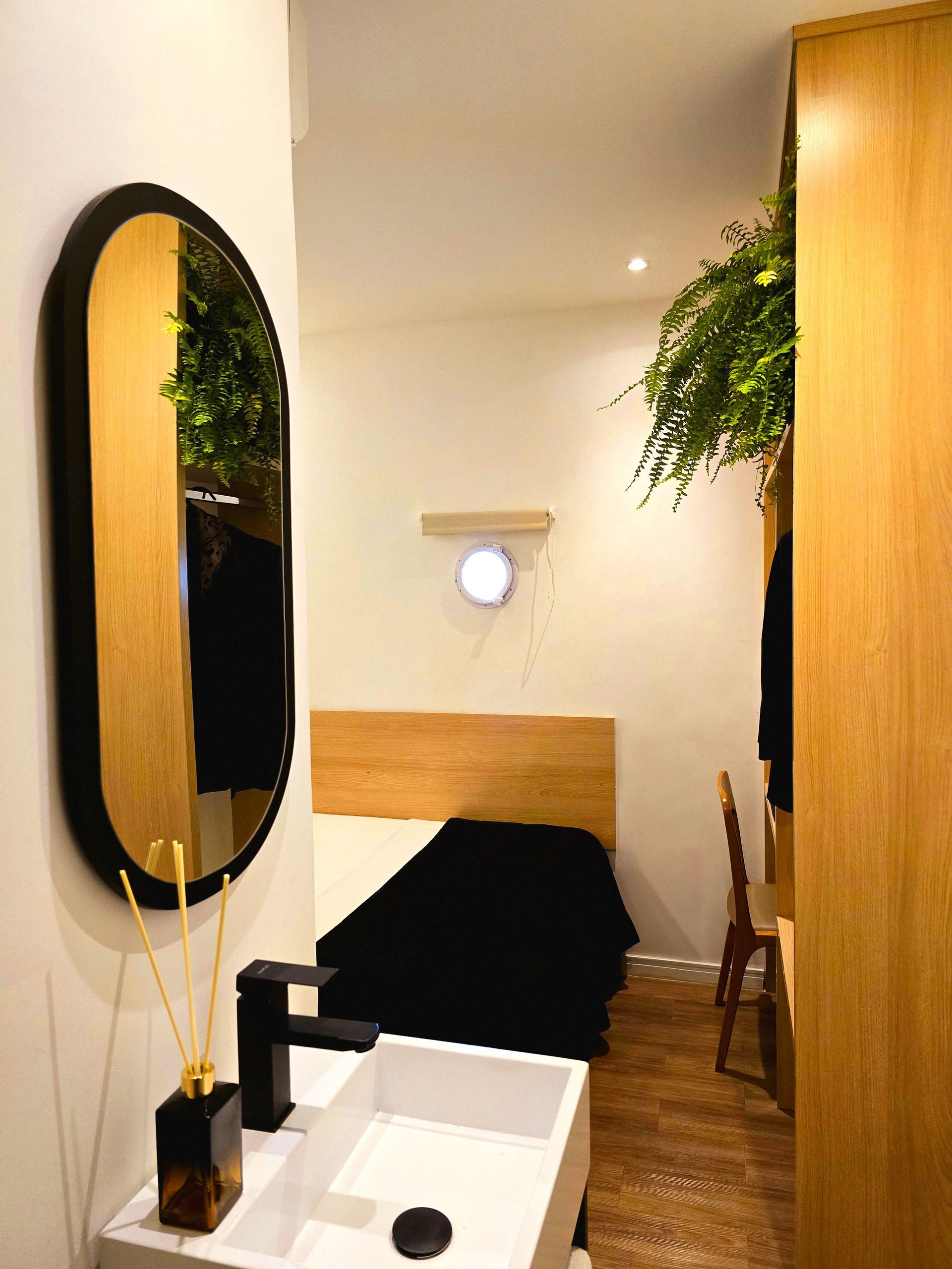A bathroom with a sink , mirror and bed.