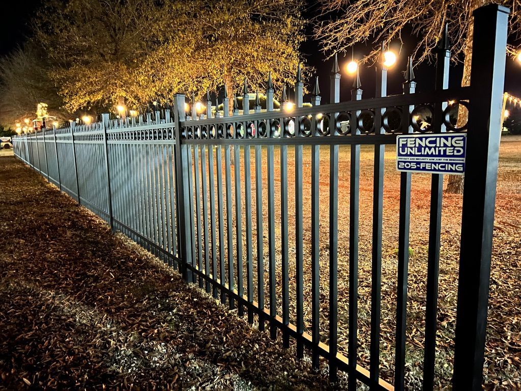Black metal fence at night with string lights.