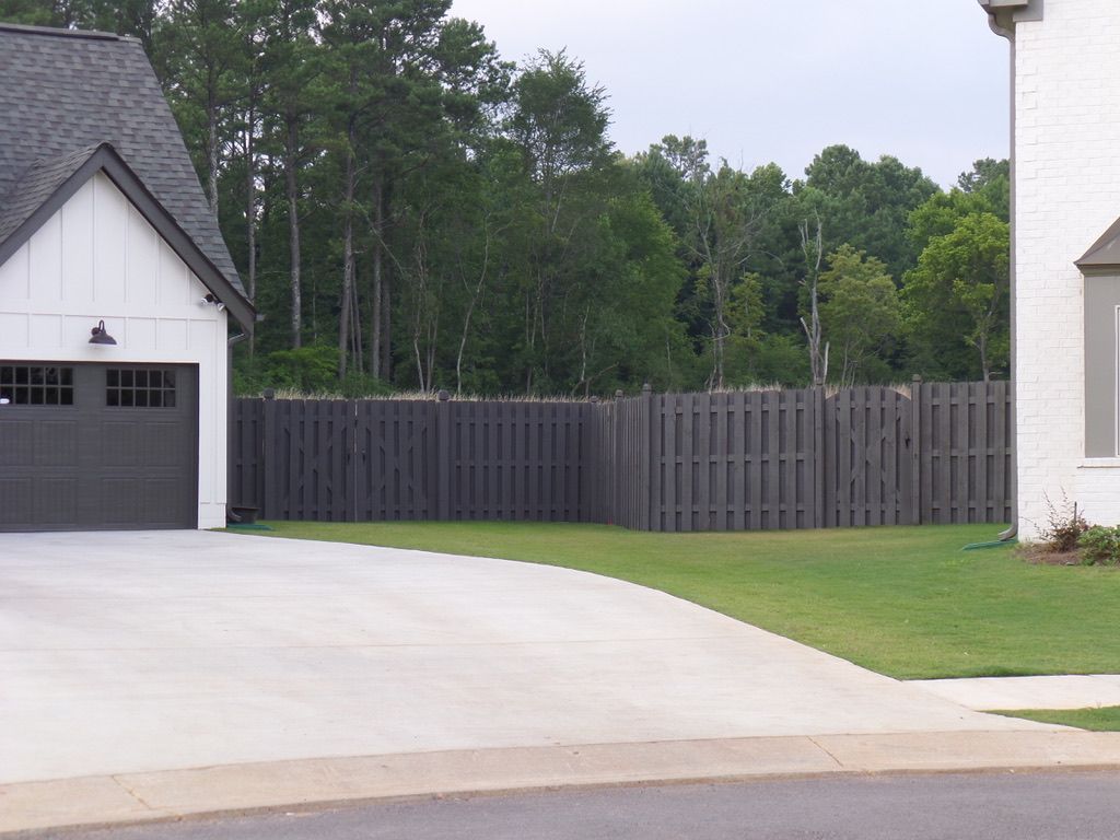 Garage and house with a dark fence and green lawn.