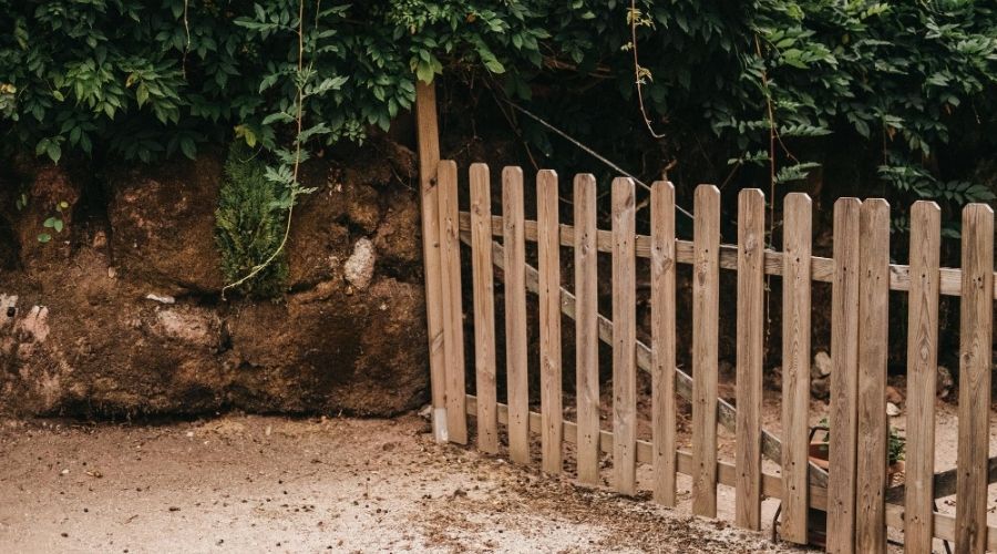 Natural wooden picket fence gate set against a stone retaining wall in Birmingham.