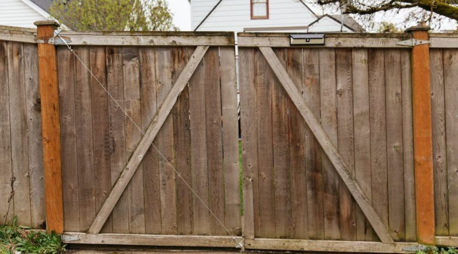 Sagging and weathered wooden double gate showing poor construction and makeshift repairs.