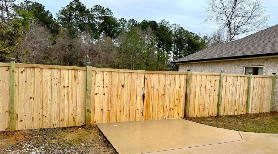 Wooden privacy fence with a double gate installed along a concrete driveway in Birmingham, Alabama.
