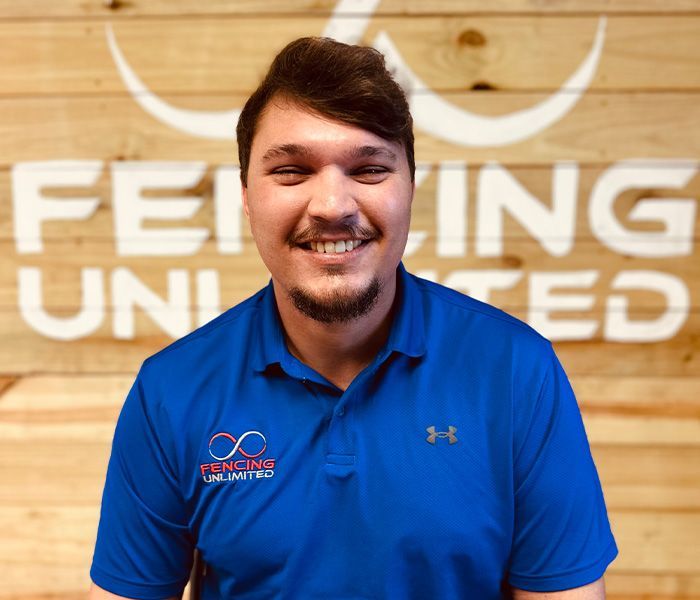 Man with a broad smile wearing a blue polo shirt in front of a