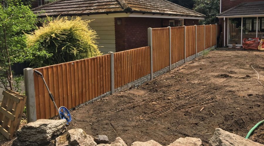 Wooden fence panels installed with concrete posts and gravel boards during yard preparation in Birmingham.
