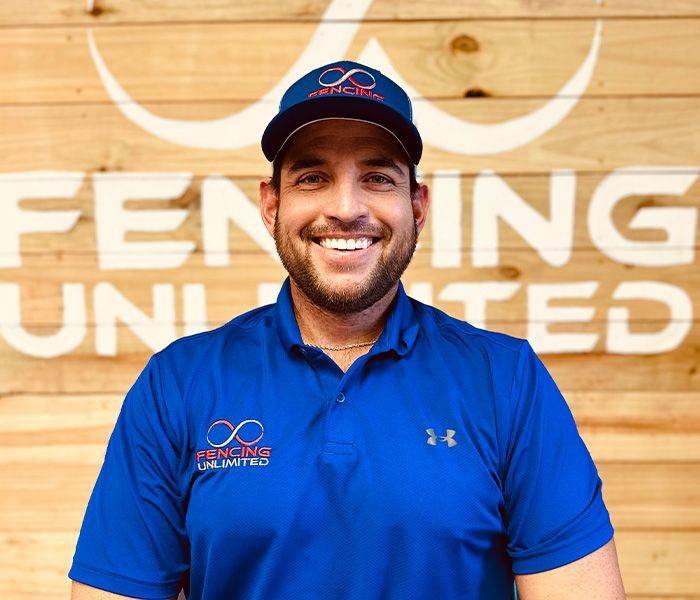 Man in blue shirt and cap smiles in front of