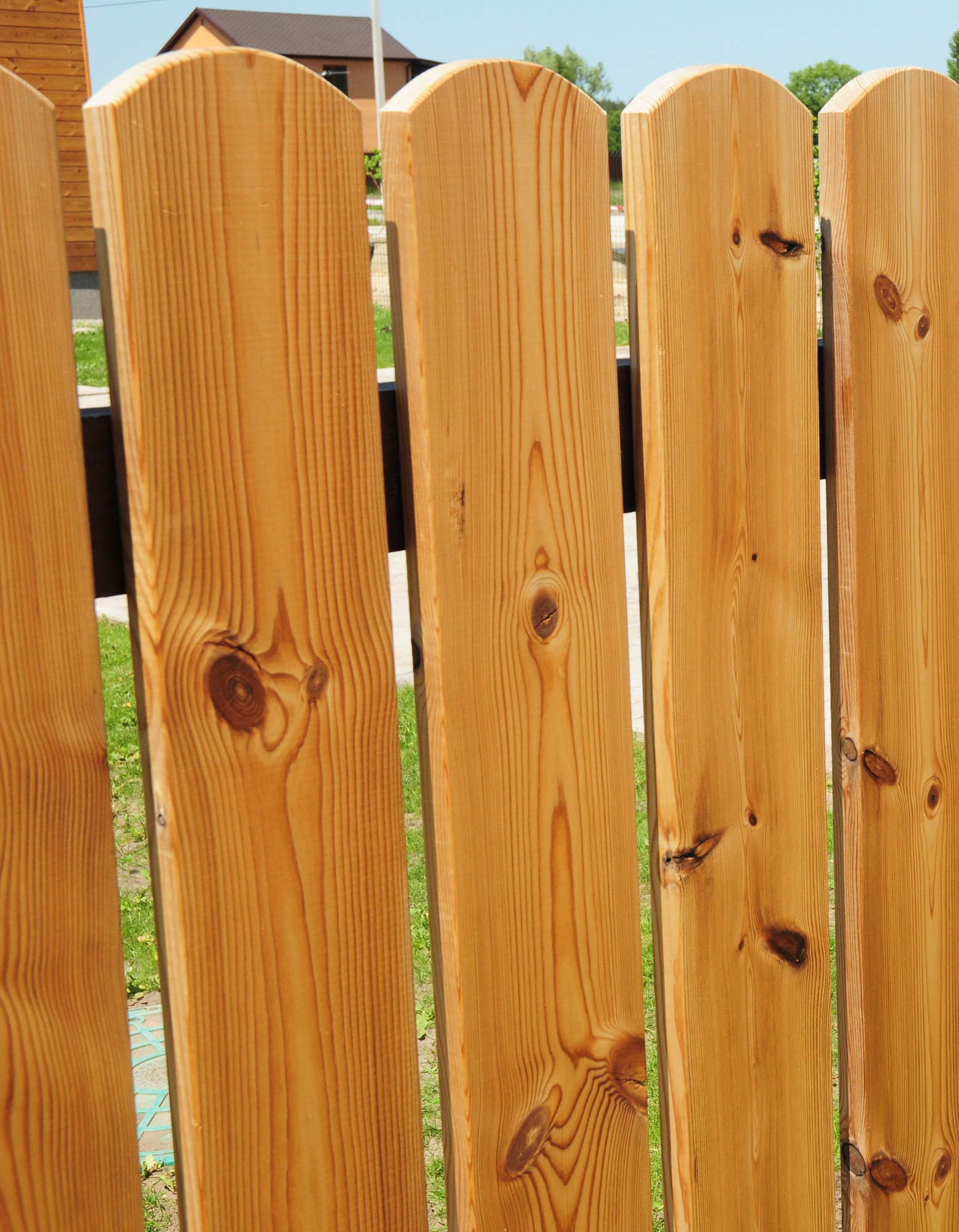 Close-up of a weathered wooden fence with vertical light-brown planks and visible knots.