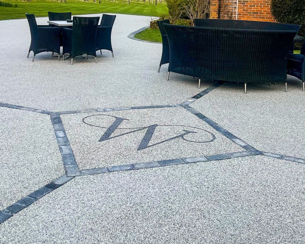 Outdoor patio with black chairs and a large fire pit on a light gray stamped concrete surface.