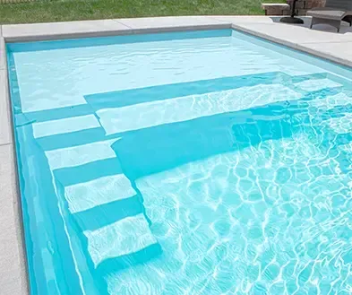 Outdoor swimming pool with shallow steps and clear blue water under sunlight