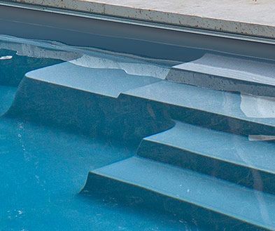 Close-up of blue pool water with white floating ice or foam along the edge