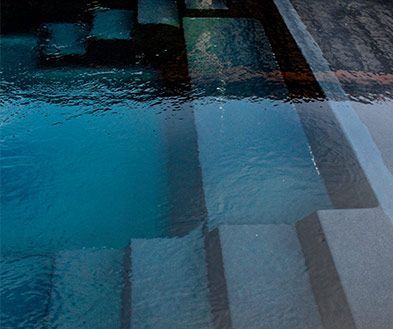 Blue-tinted abstract view of wet pavement with white lane markings and reflections