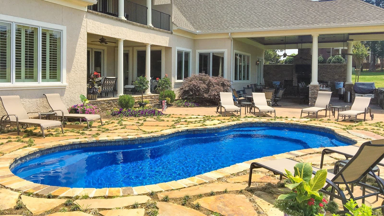 Backyard pool beside a patio with lounge chairs and a covered seating area at a house