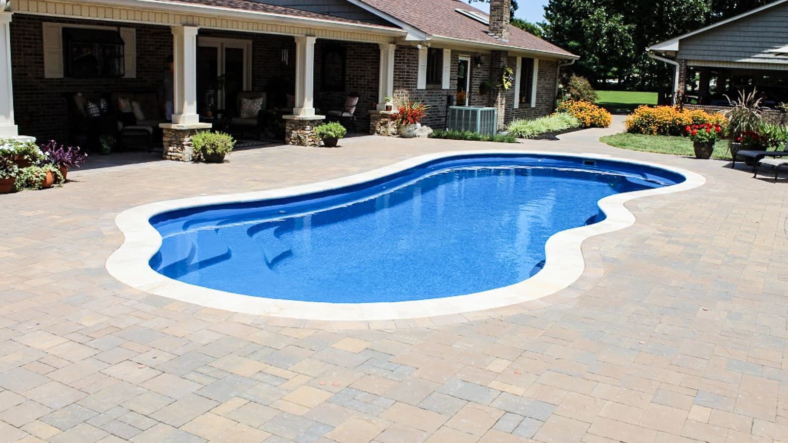 Backyard swimming pool with blue water beside a patio and house