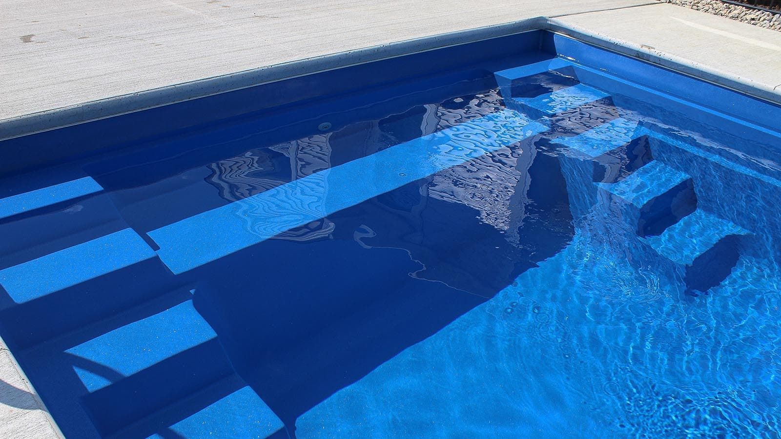 Blue swimming pool with steps and underwater benches along the side