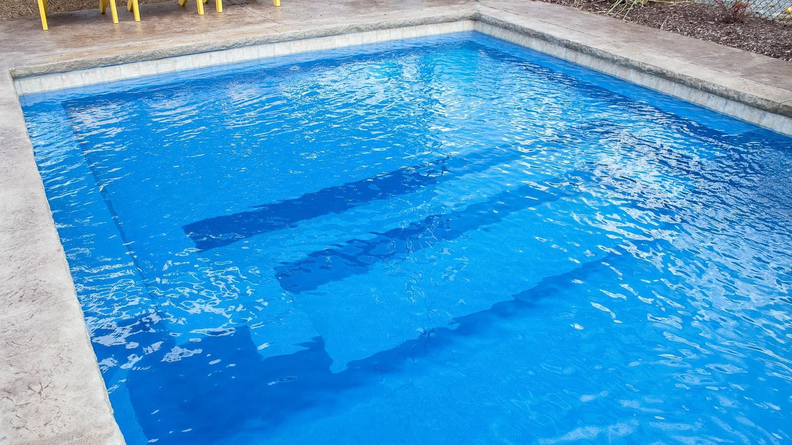 Blue swimming pool with submerged steps and rippling water