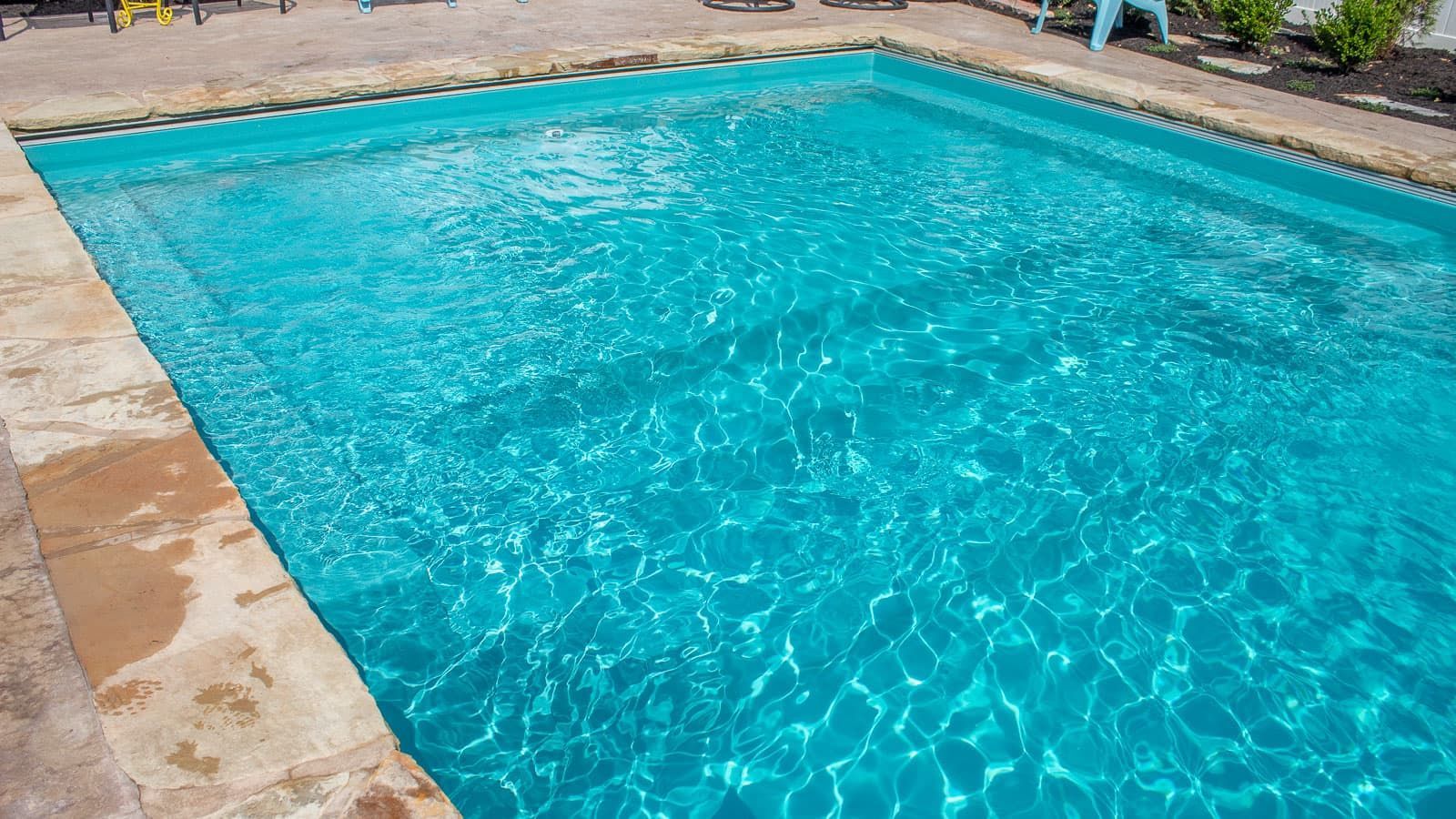 Clear turquoise swimming pool with stone deck along the edge