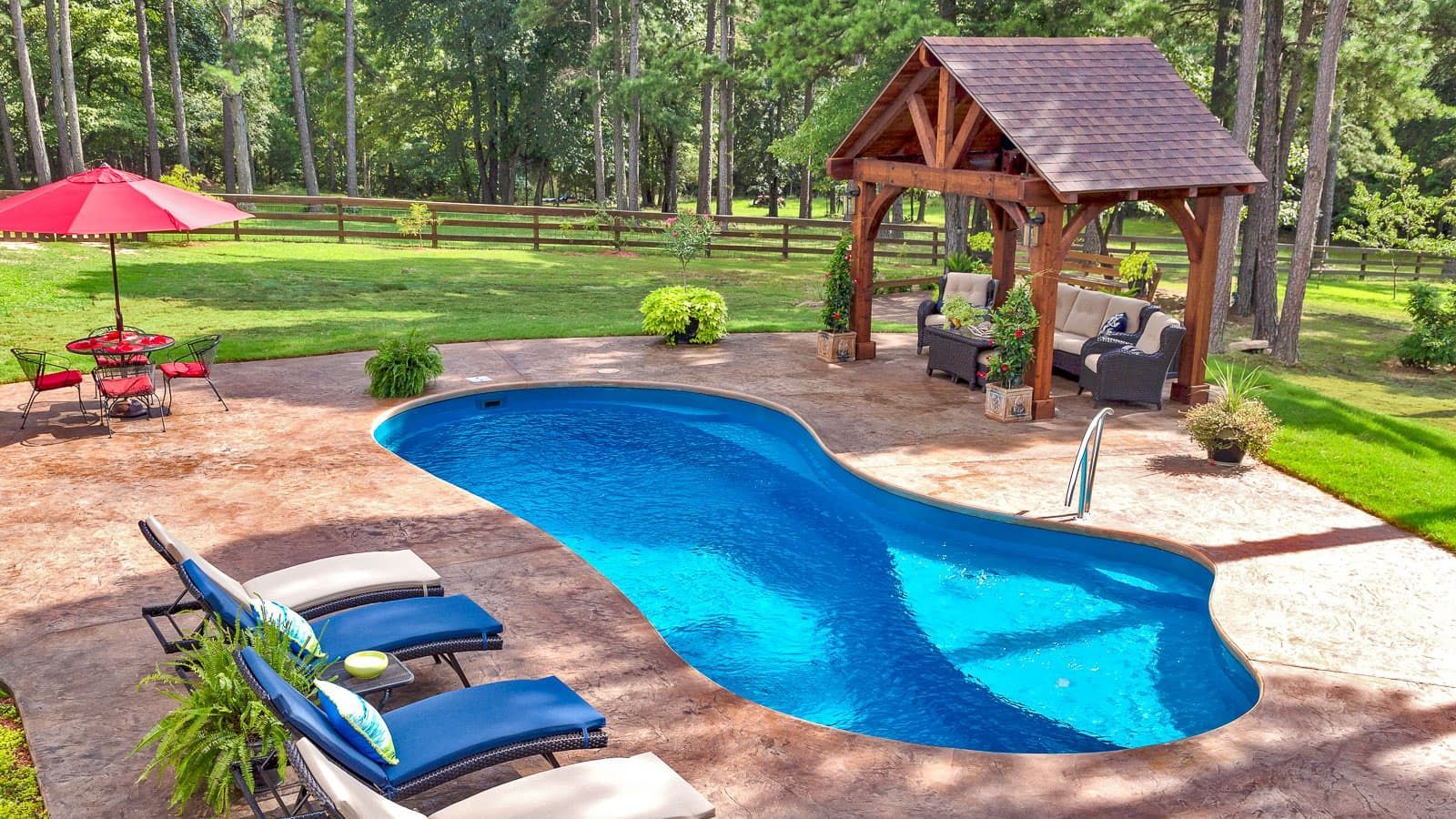 Backyard pool with blue water, lounge chairs, red umbrella, and a wooden gazebo on a brick patio