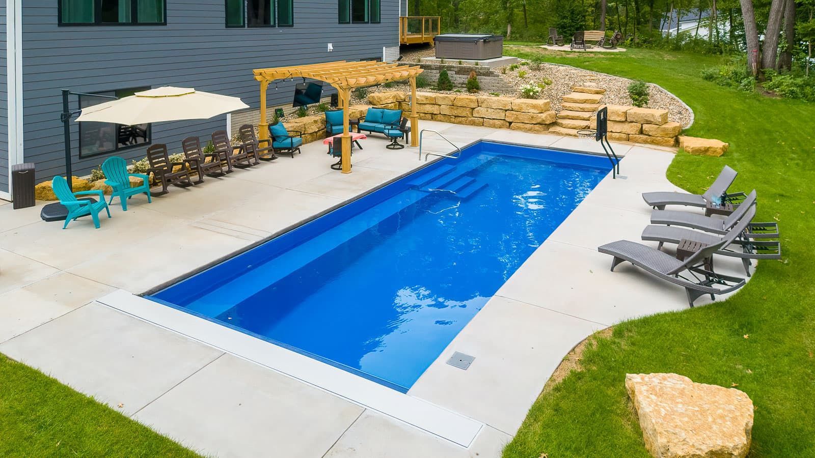 Backyard pool with blue water, lounge chairs, umbrellas, and stone patio