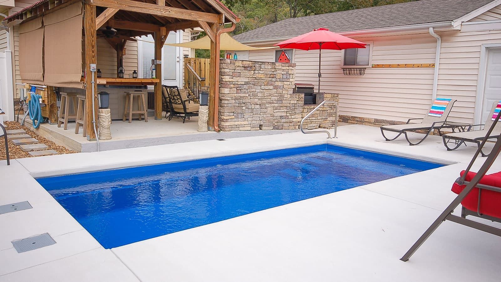 Backyard pool with blue water, white deck, red umbrella, and wooden gazebo seating area