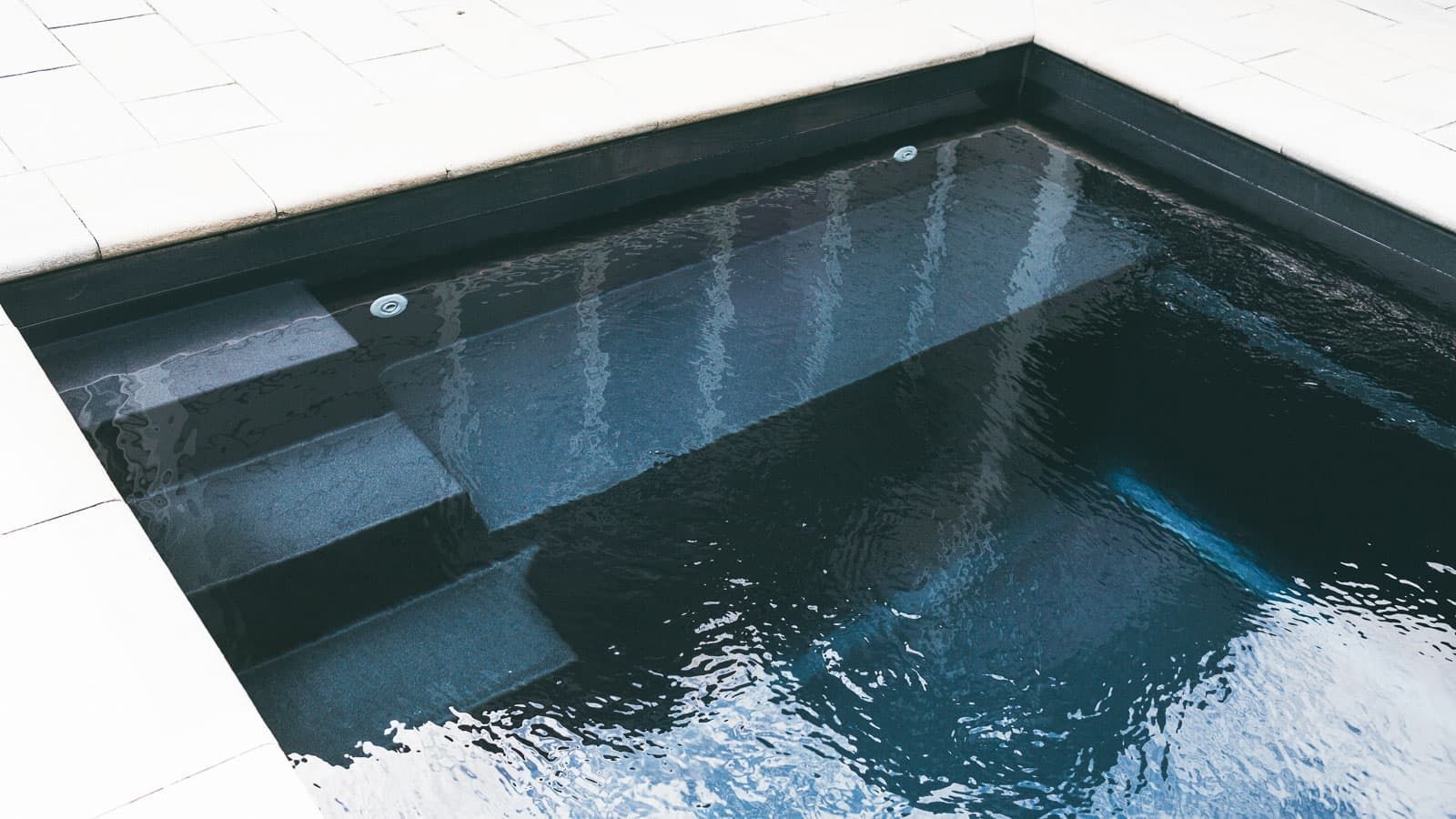 Modern indoor pool with dark blue water and tiled steps