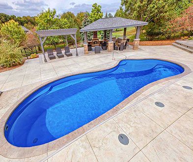 Blue swimming pool beside two shaded pavilions on a tiled patio