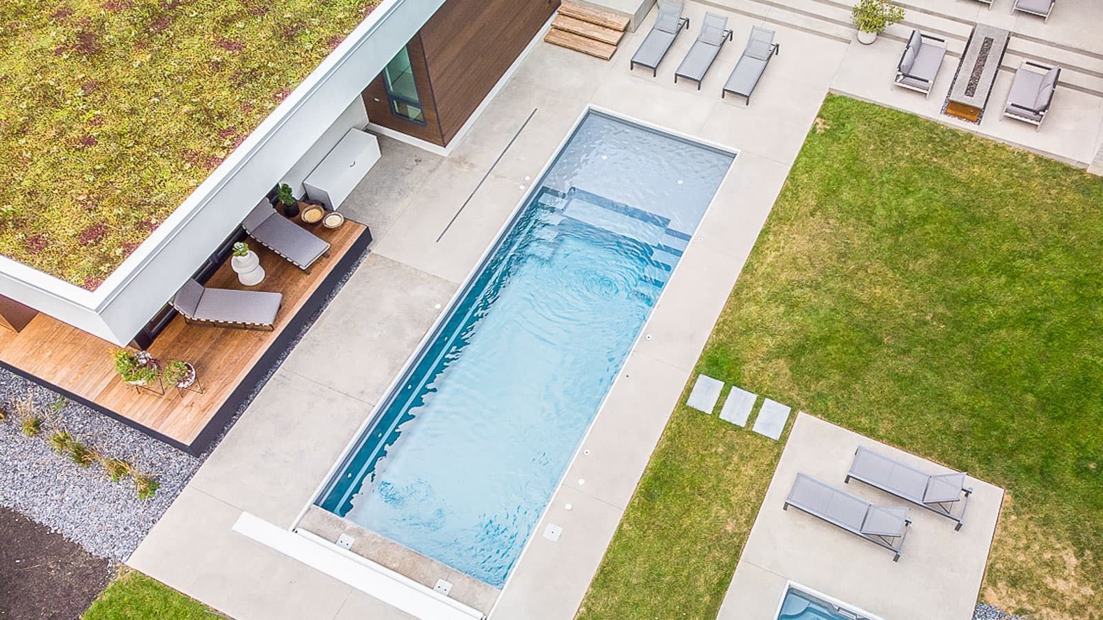 Overhead view of a modern backyard pool with lounge chairs and a patio area