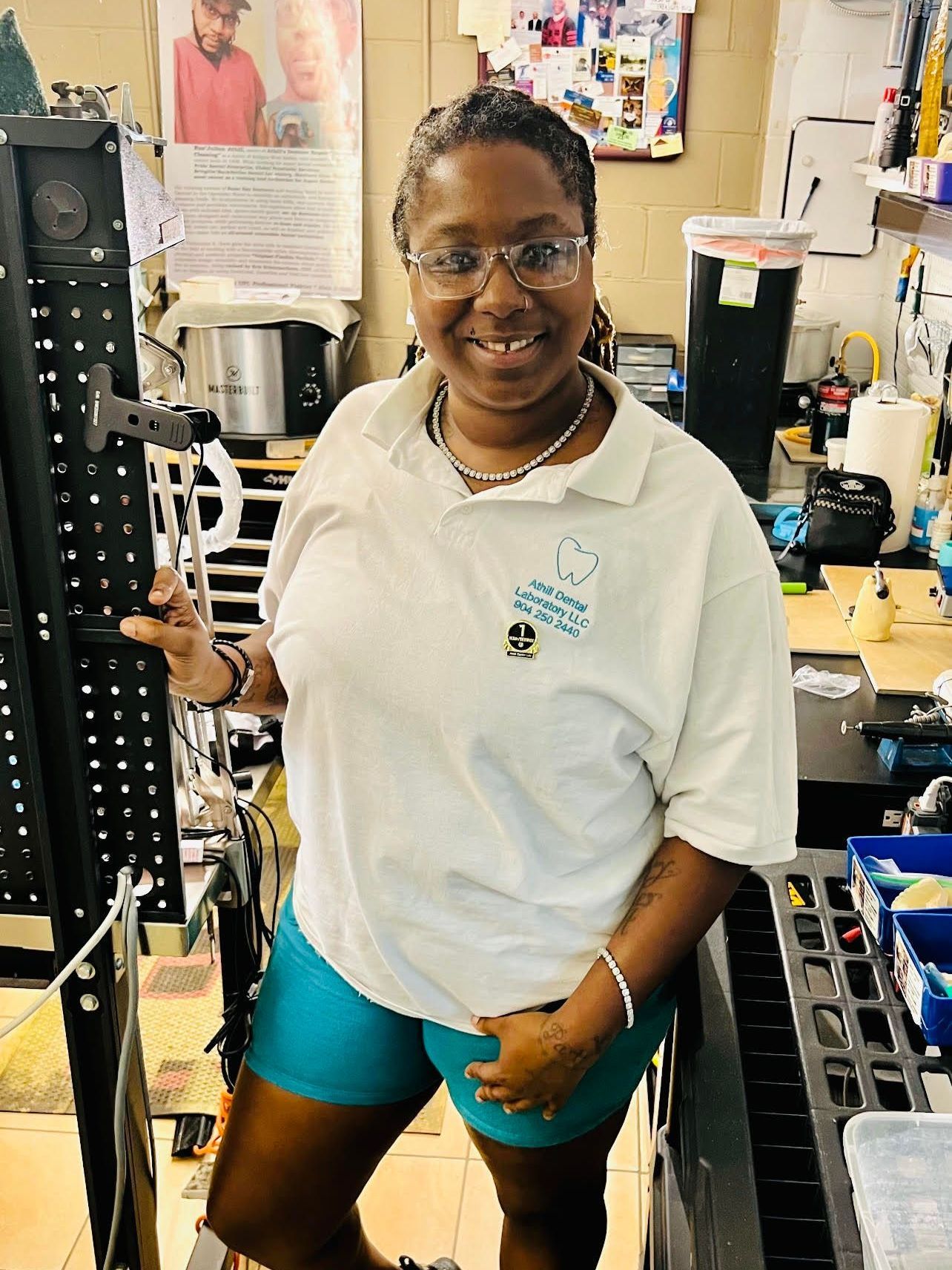 A woman in a white shirt and blue shorts is standing in a room holding a wrench.