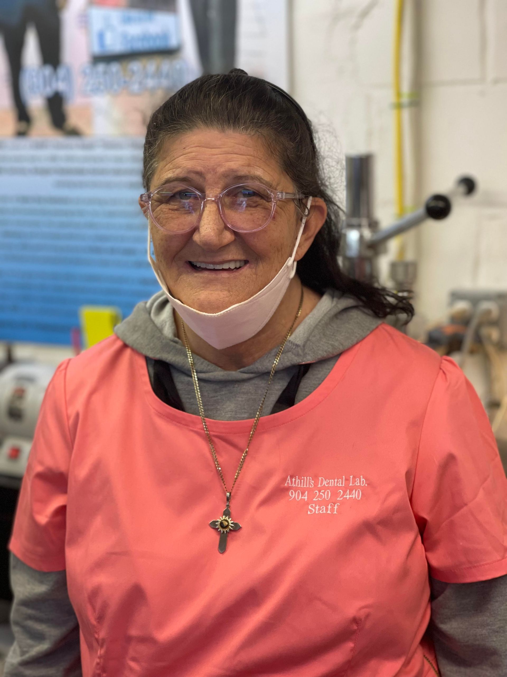A woman wearing a mask and glasses is smiling for the camera.