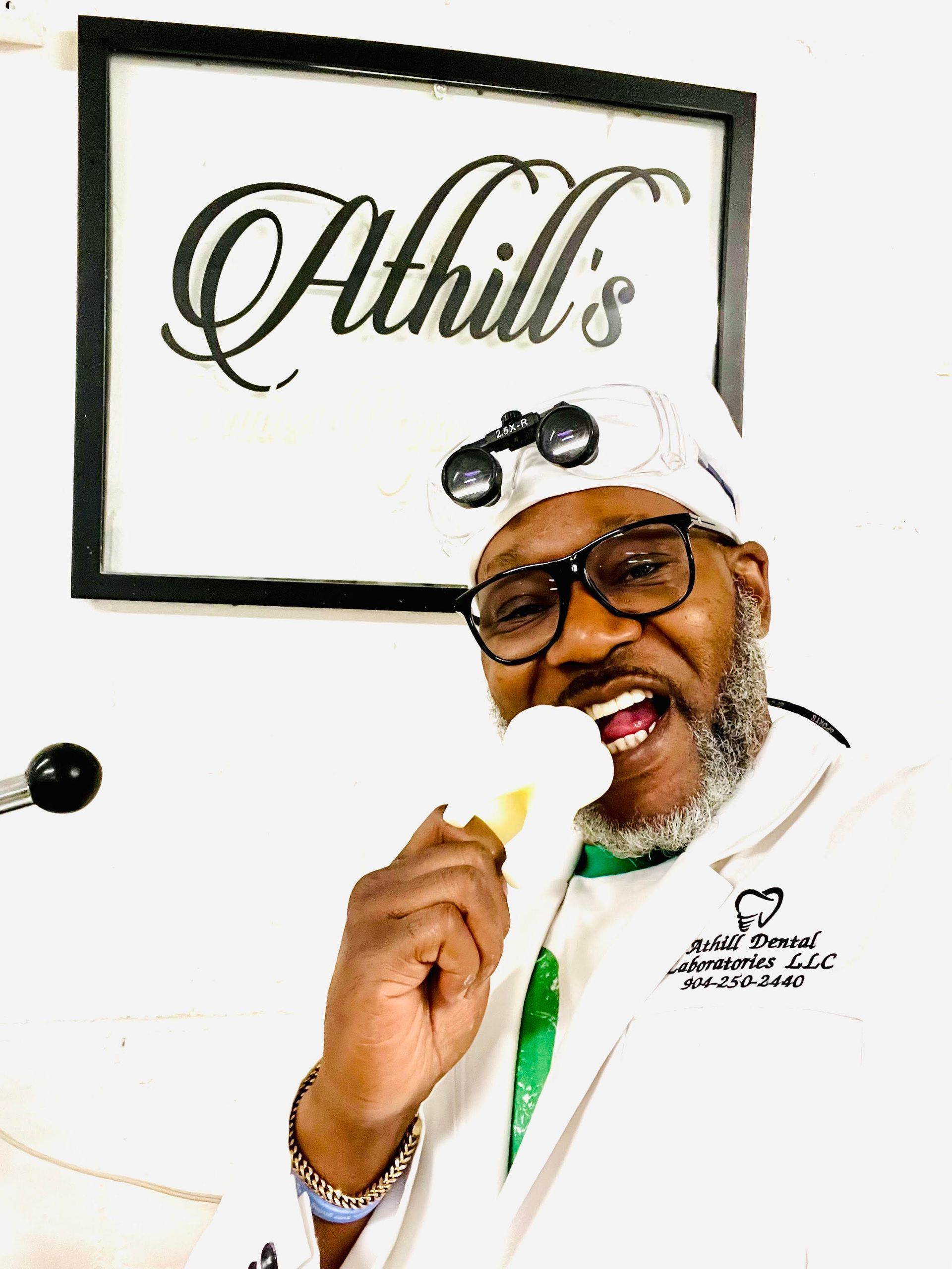 A man in a chef 's hat is holding a piece of food in front of a sign that says athill 's