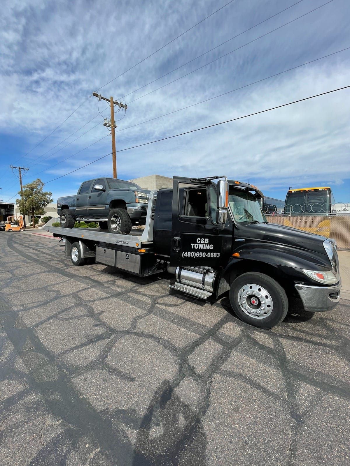 A tow truck with a truck on the back is parked on the side of the road.