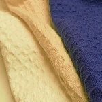 Three different colored towels are stacked on top of each other on a table. Three different colored towels are stacked on top of each other on a table.