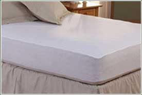 A bed with a white mattress protector on it. A bed with a white mattress protector on it.