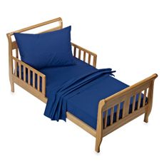 A wooden toddler bed with blue sheets and pillows. A wooden toddler bed with blue sheets and pillows.