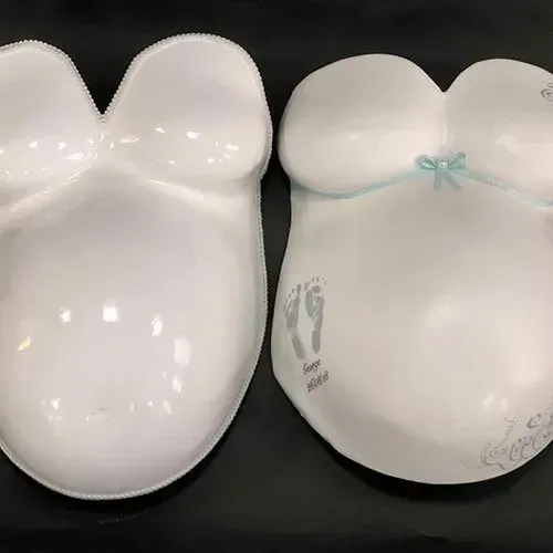Two white plates in the shape of a pregnant woman 's belly.