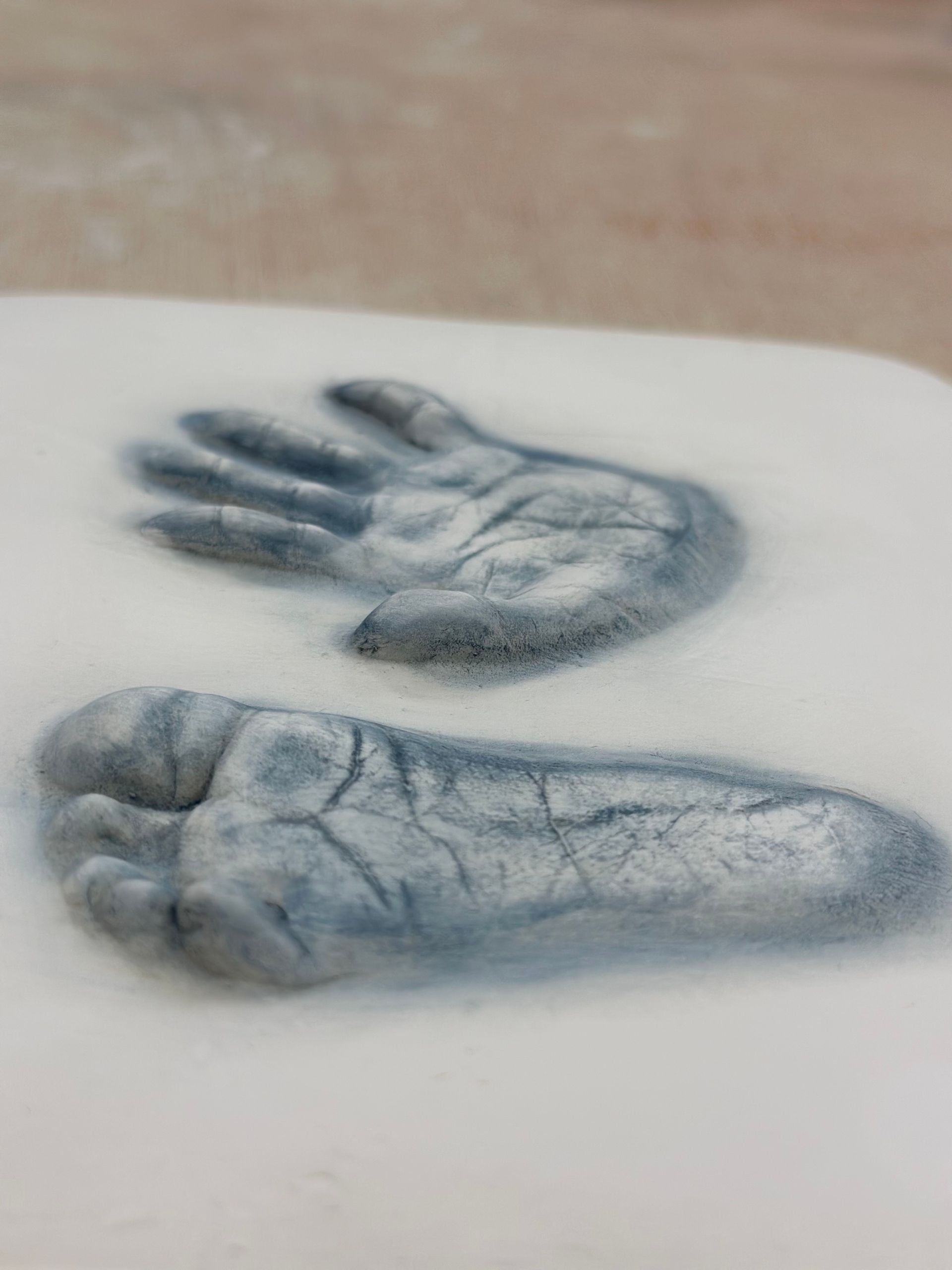 A close up of a hand and foot print on a white surface.