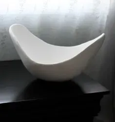 A white bowl is sitting on top of a black table.