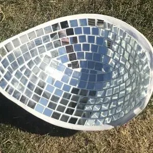 A mosaic bowl is sitting on top of a lush green field.