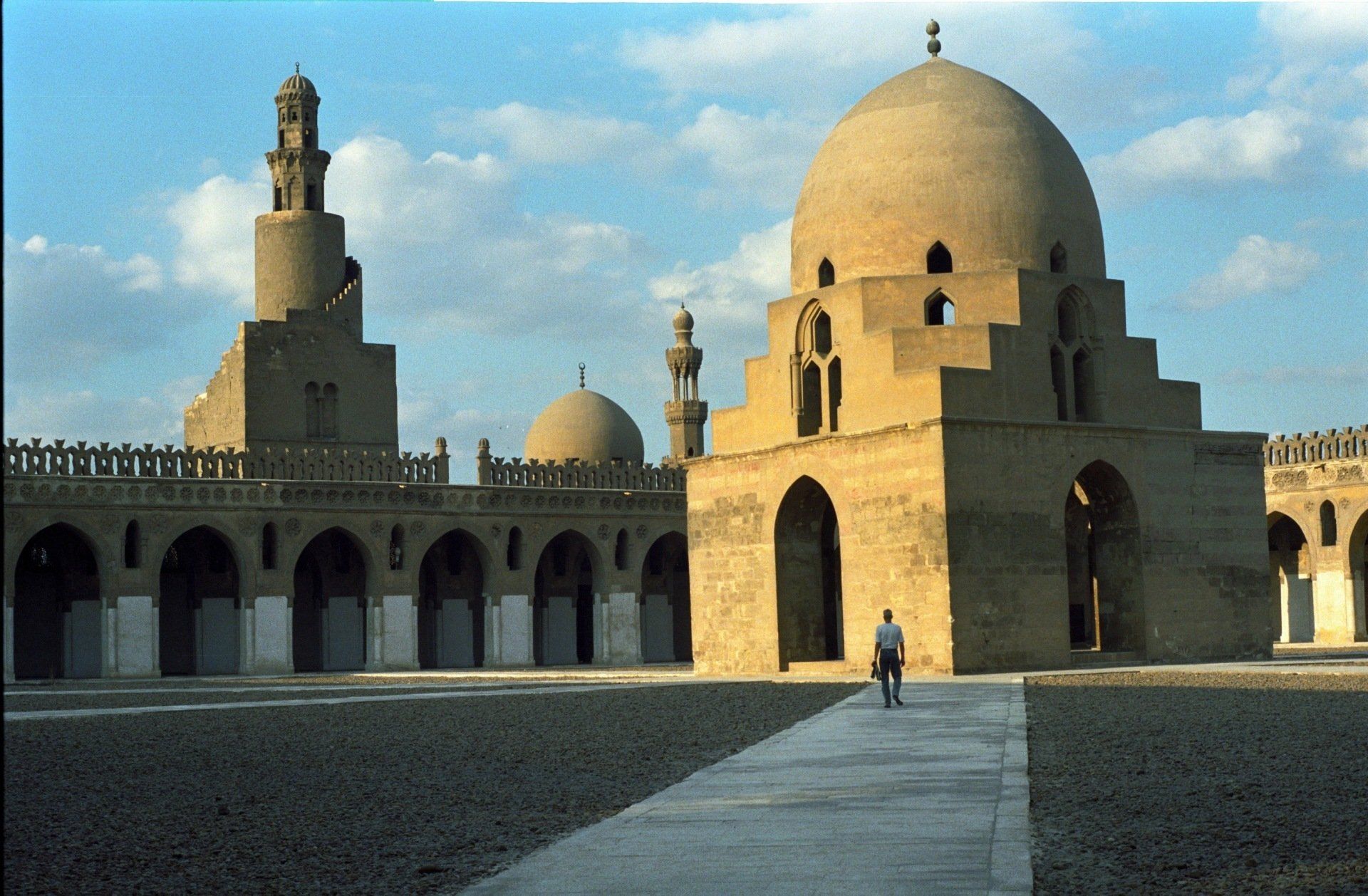 Binnenplaats van de Ibn Tulun-moskee in Caïro, Egypte, met koepel, minaret en een persoon die fietst.