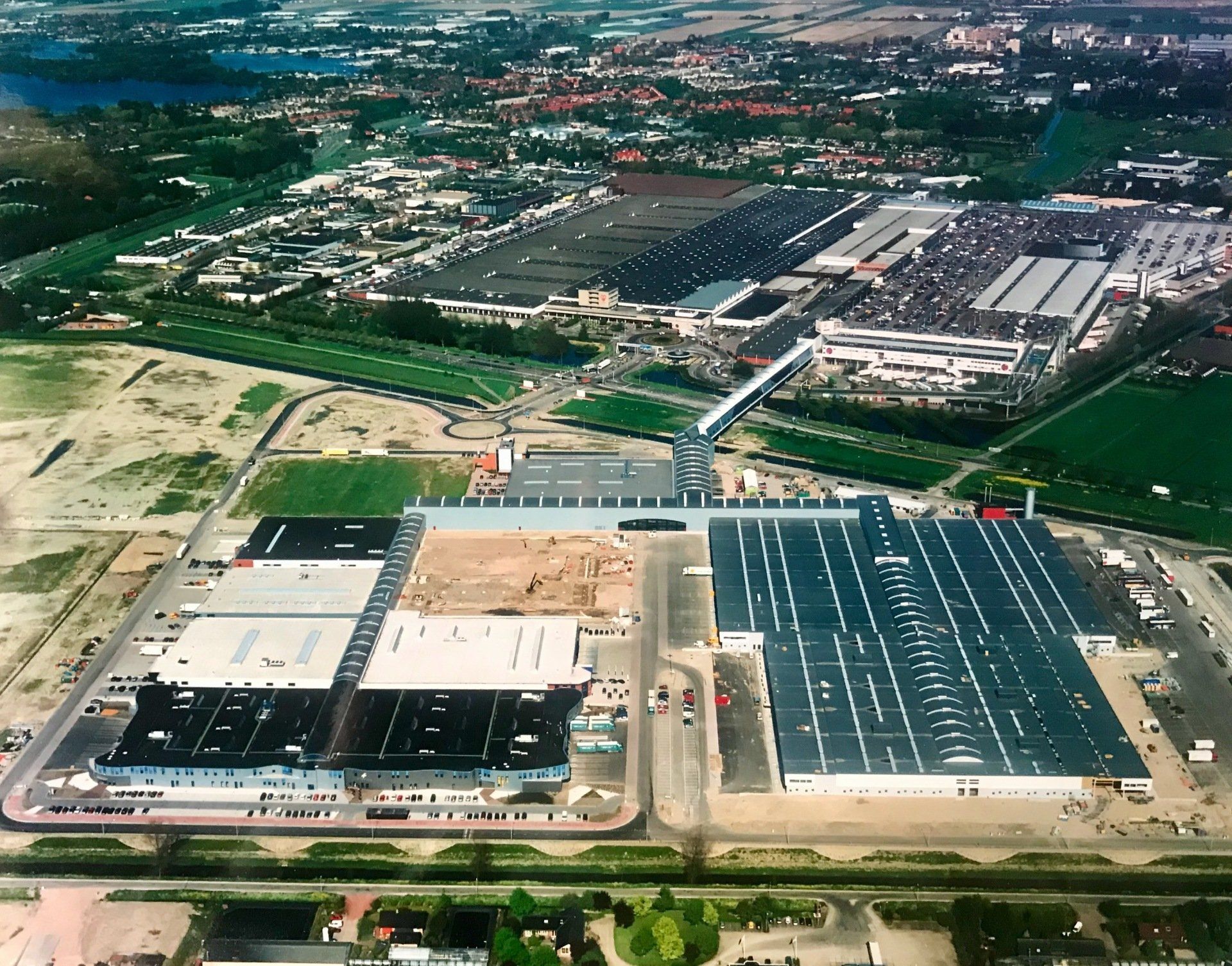 Luchtfoto van een groot industriecomplex met diverse gebouwen, wegen en parkeerterreinen.