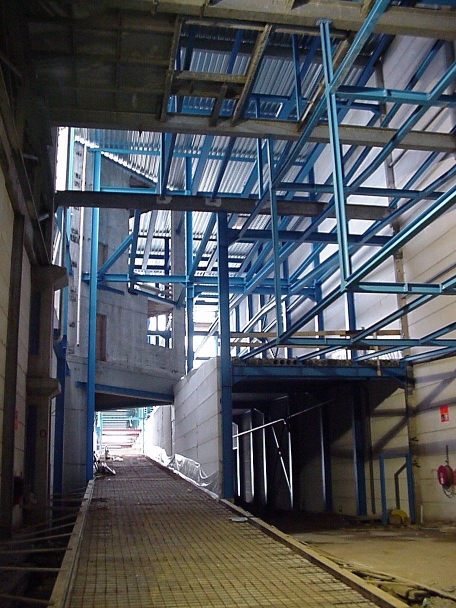 Interieur van een industriegebouw, blauw metalen frame en betonnen constructies, bakstenen looppad.