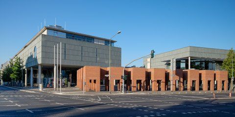 Modern bibliotheek, met bakstenen en betonnen constructies en een helderblauwe hemel.