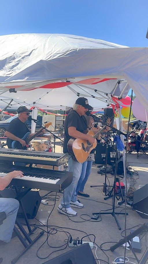 A group of men are playing instruments on stage under a tent.