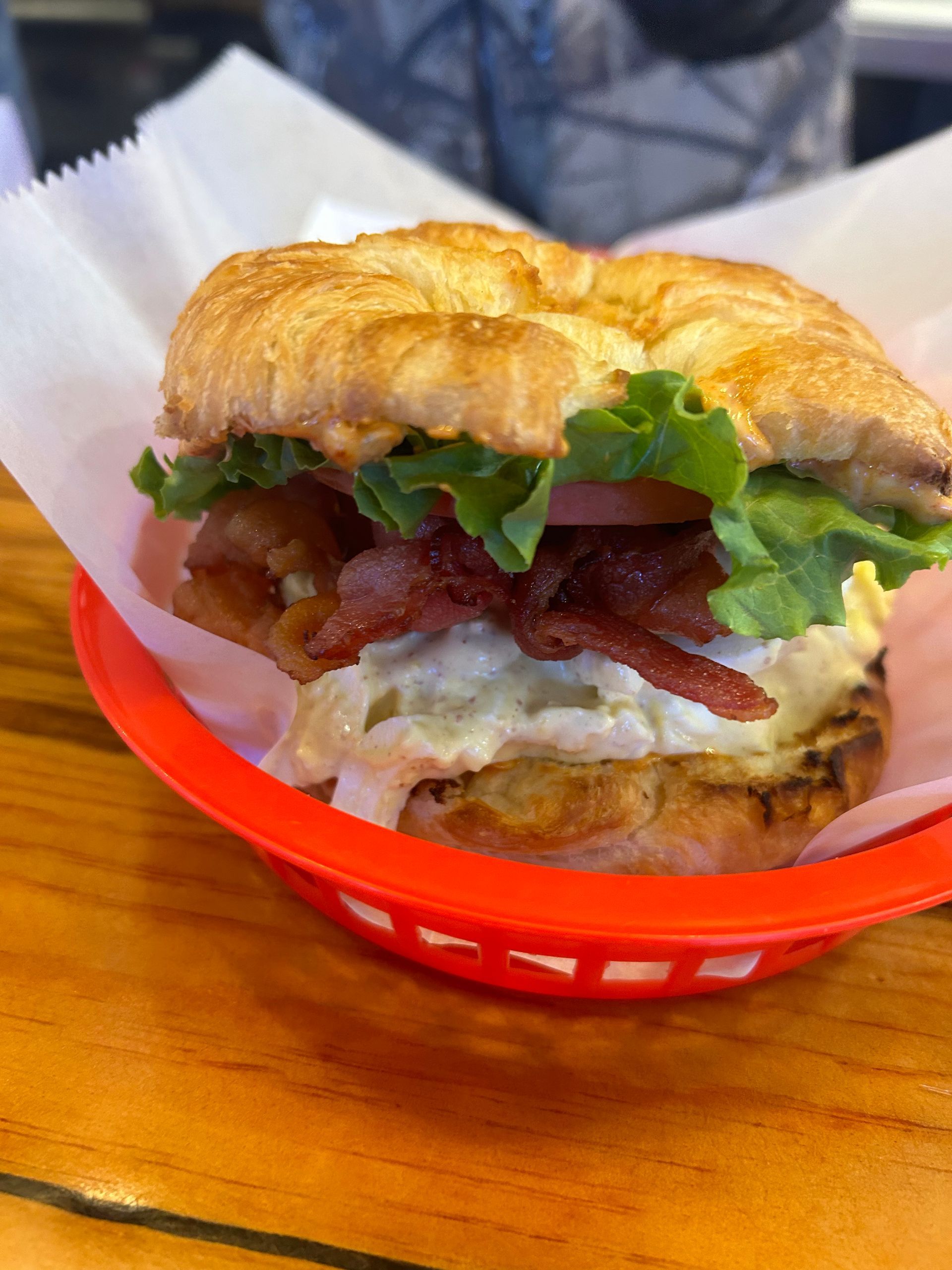 A close up of a sandwich in a red basket on a table.