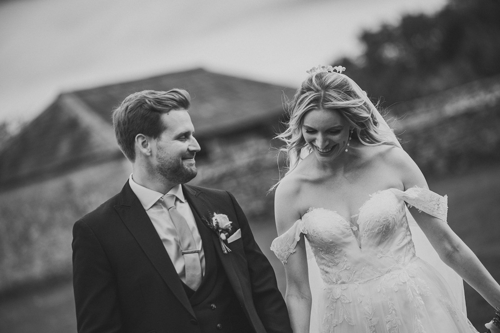 A black and white photo of a bride and groom holding hands.