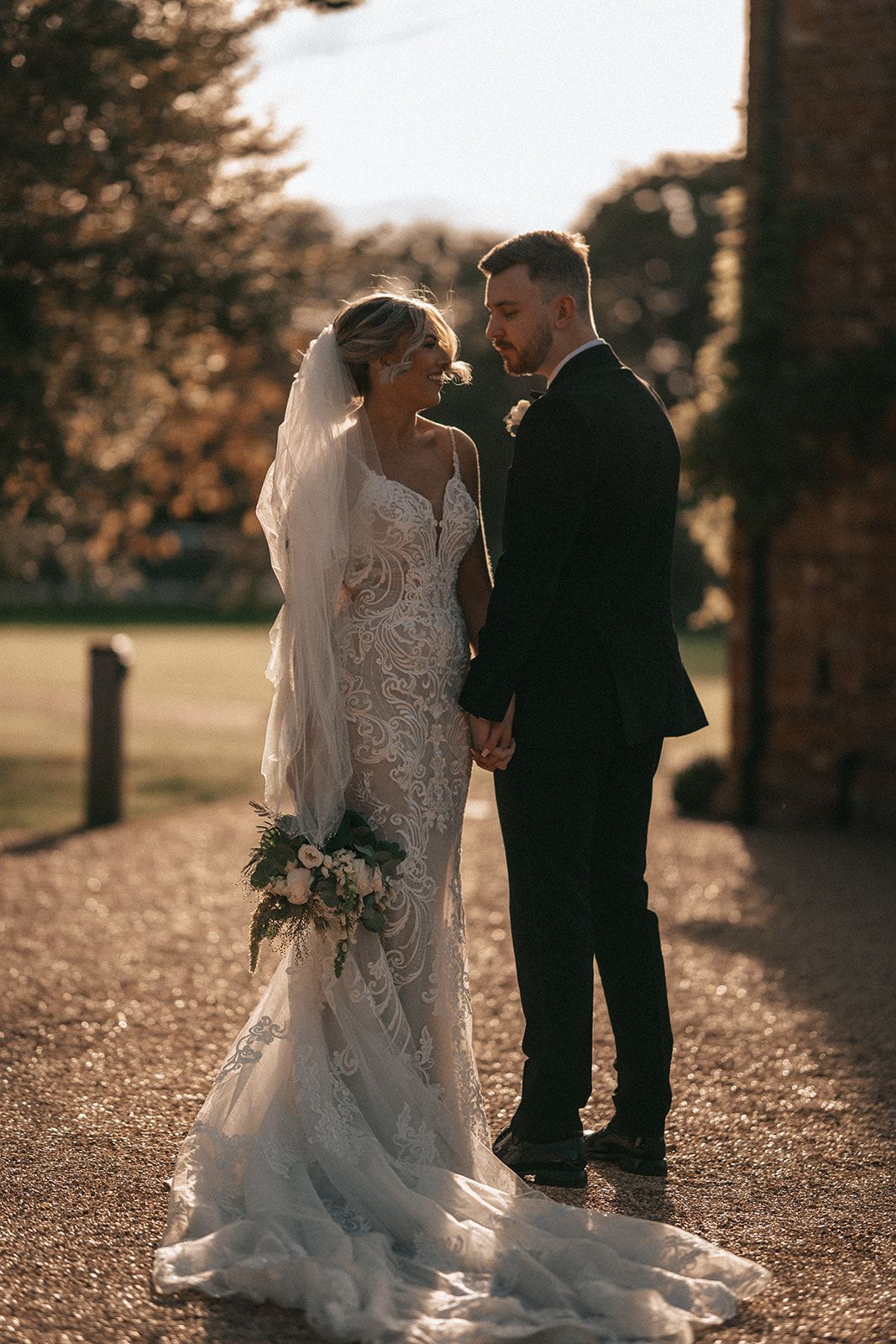 A bride and groom are holding hands and looking at each other.