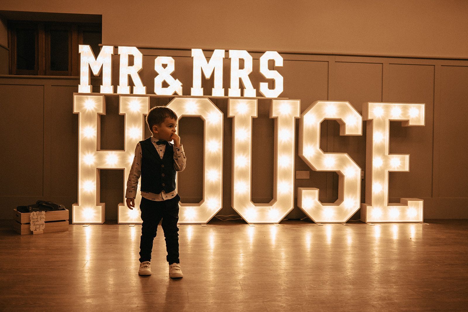 A little boy is standing in front of a sign that says mr and mrs house.