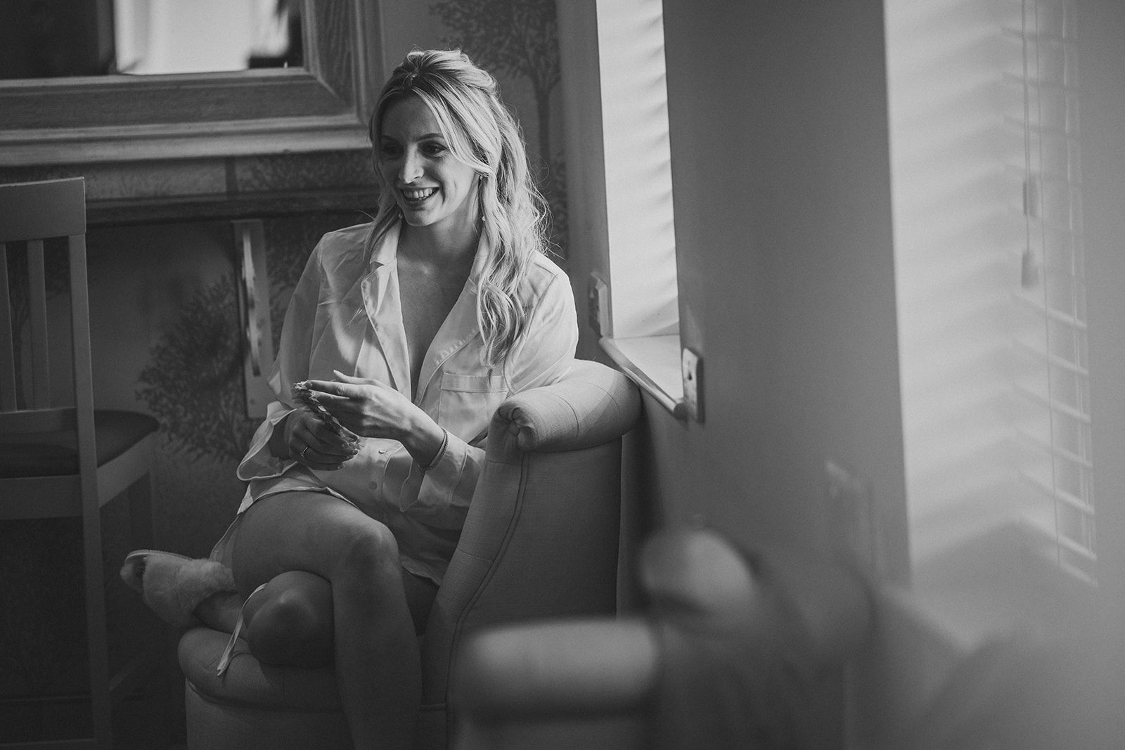 A woman is sitting in a chair in front of a window.