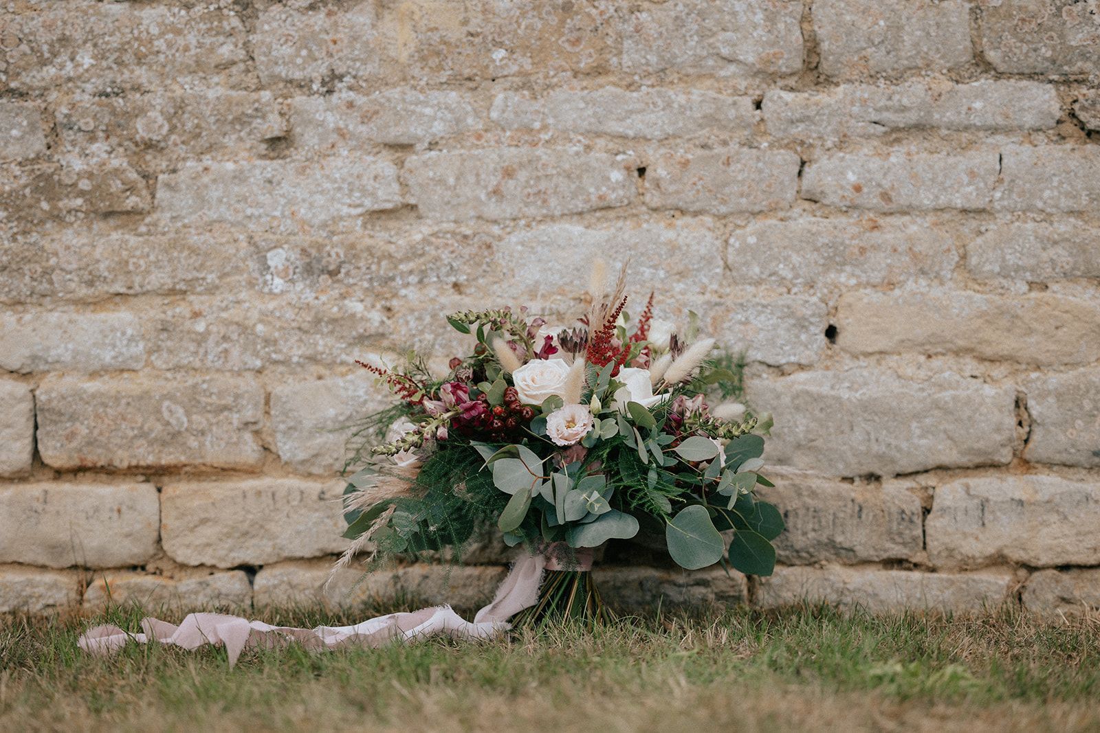 A bouquet of flowers is sitting in front of a stone wall.