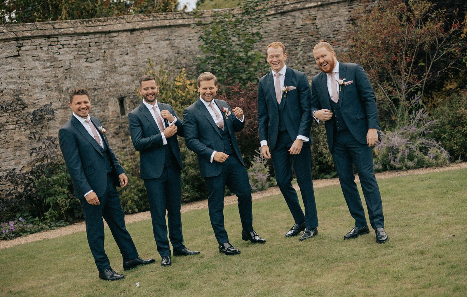 A group of men in suits are standing next to each other on a lush green field.