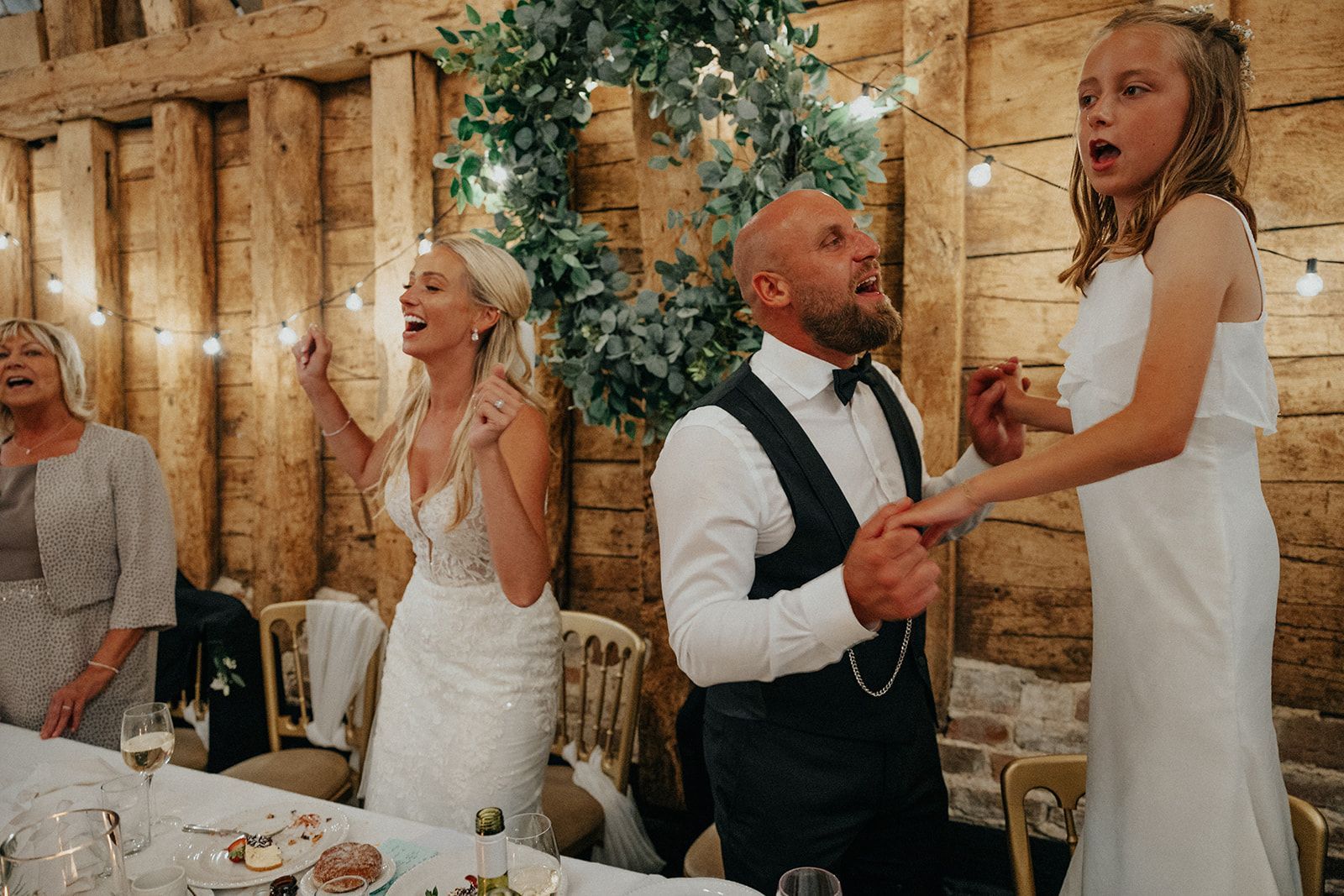 A bride and groom are dancing with their daughter at their wedding reception.